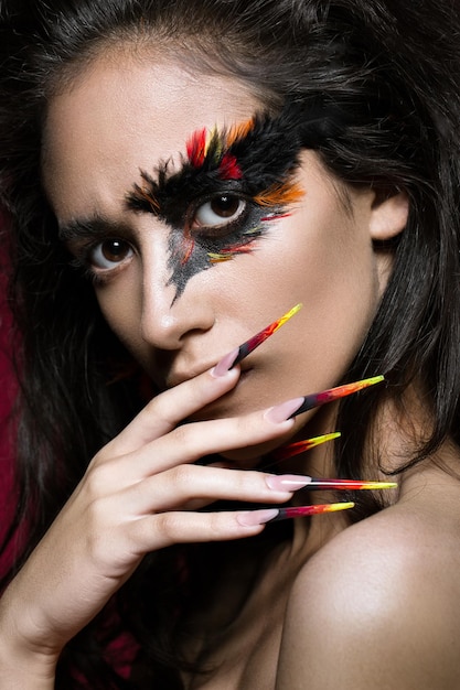 Piękna dziewczyna na obrazku ptaka Feniksa z kreatywnym makijażem i długimi paznokciami Manicure projekt piękna twarz