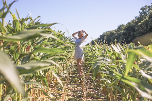Piękna dziewczyna na polu kukurydzy latem nad błękitne niebo jasne. Szczęśliwa młoda zdrowa kobieta z przyrodą na zewnątrz. Bieganie i wirująca kobieta. Latający. Wolna, koncepcja wolności, środowisko