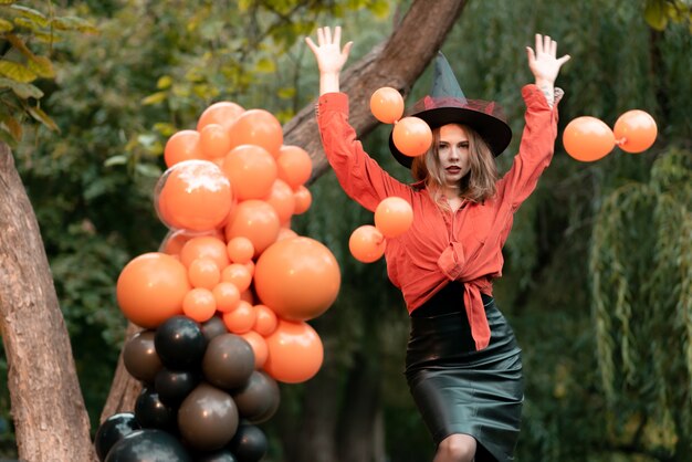 Piękna dziewczyna o chytrym spojrzeniu. Ubrania na Halloween. Rzuca balony i uśmiechy