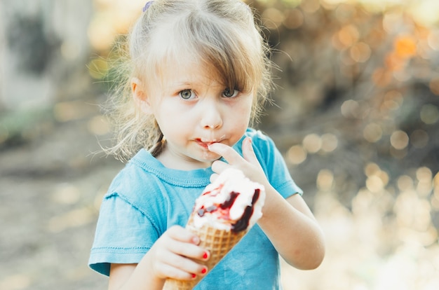 Zdjęcie piękna dziewczyna pięć lat je lody w przyrodzie, róg z owocami