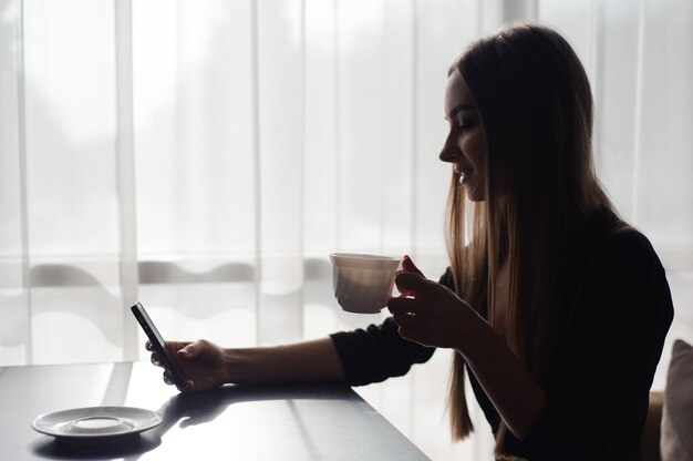 Piękna Dziewczyna Pije Herbaty I Używa Telefon Komórkowego