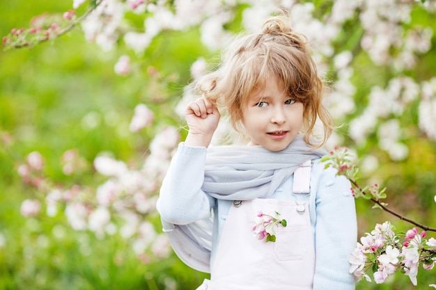 Piękna dziewczyna preteen z długimi blond włosami cieszy się wiosennym kwitnieniem jabłek. Mała dziewczynka w wieku przedszkolnym w kwiaty drzewa ogrodowe. Wiosna. Skopiuj miejsce