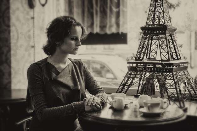Zdjęcie piękna dziewczyna przy filiżance kawy w kawiarni z odrobiną sepii