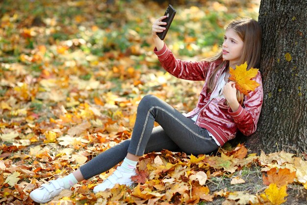 Piękna dziewczyna robi selfie przez smartfon w jesiennym parku