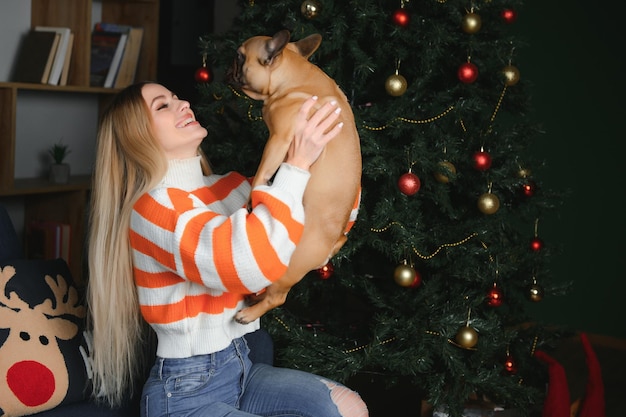 Piękna dziewczyna siedzi na kanapie z psem na tle świąt Bożego Narodzenia
