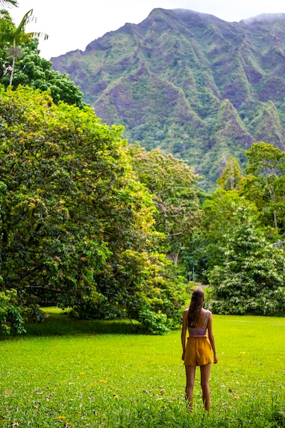 piękna dziewczyna spaceruje po ogrodzie botanicznym Ho'omaluhia, podziwiając potężne góry na oahu