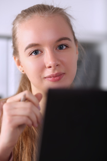 Piękna dziewczyna trzyma długopis siedzi obok laptopa