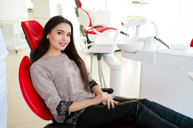 Piękna dziewczyna uśmiecha się na fotelu dentystycznym.