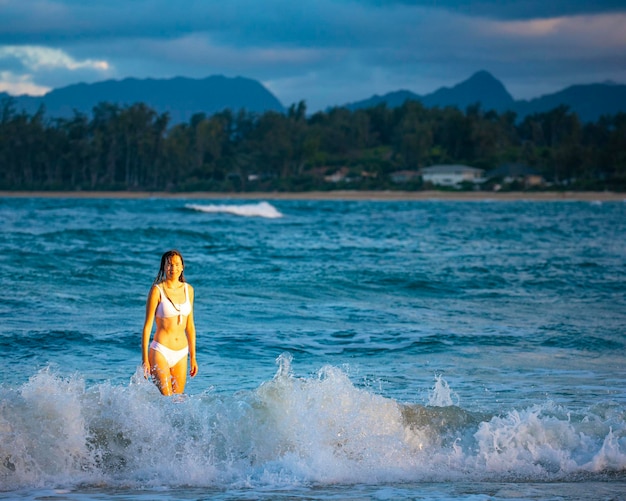 Zdjęcie piękna dziewczyna w białym bikini pływa w oceanie na rajskiej plaży na oahu na hawajach