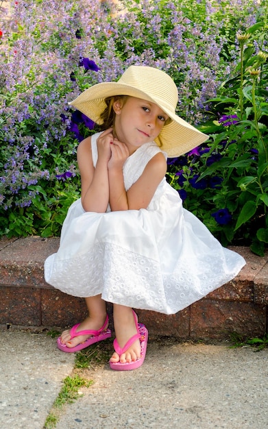 Zdjęcie piękna dziewczyna w białym i słomkowym kapeluszu uśmiecha się do kamery