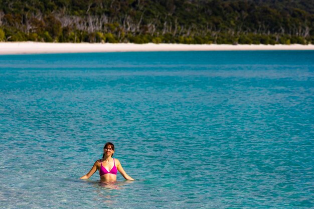 Piękna dziewczyna w bikini cieszy się kąpielą w turkusowej wodzie na plaży Whitehaven, australia