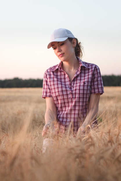 Piękna dziewczyna w czapce z daszkiem na polu żyta. Młoda dziewczyna w polu pszenicy na tle zachodu słońca