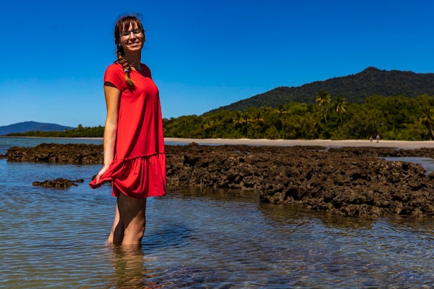 piękna dziewczyna w czerwonej sukience stoi w wodzie rafy koralowej w parku narodowym daintree, australia