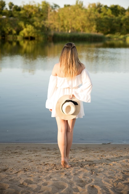 Zdjęcie piękna dziewczyna w kapeluszu stoi na brzegu kapelusza w dłoni