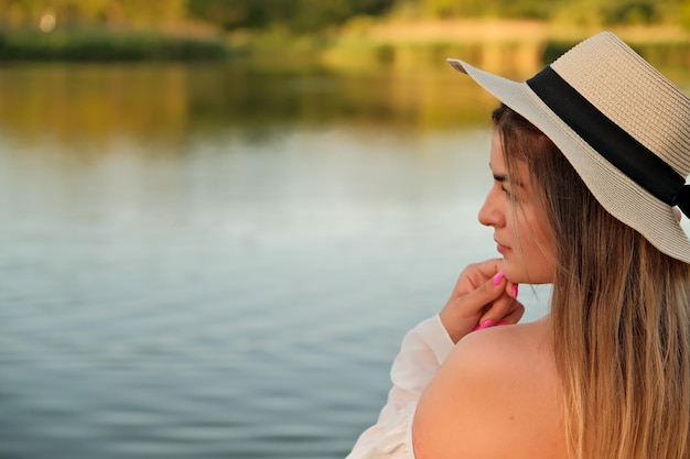 Piękna dziewczyna w kapeluszu stoi na brzegu kapelusza w dłoni
