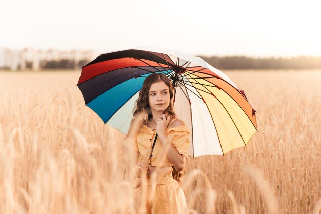 Piękna dziewczyna w przyrodzie latem z kolorowym parasolem