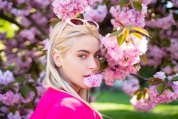 Piękna dziewczyna w różowych kwiatach w letnim parku kwiatów