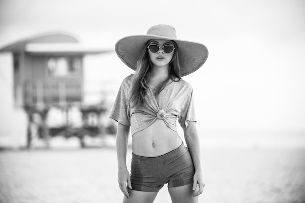 Piękna dziewczyna w słomkowym kapeluszu, ciesząc się opalaniem w South Beach Miami, młoda opalona kobieta ciesząca się bree