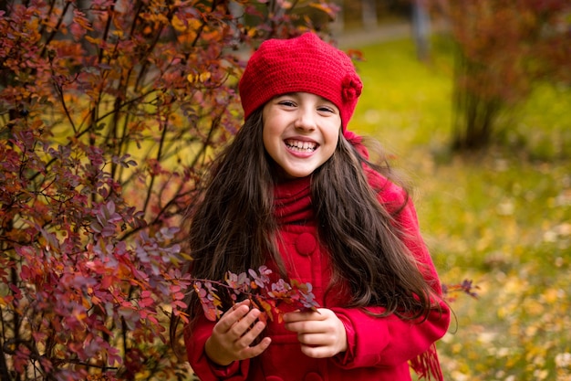 Piękna dziewczyna w słonecznym jesiennym parku. Dziecko bawiące się w parku na jesień. Jesienny nastrój. Zdjęcie wysokiej jakości