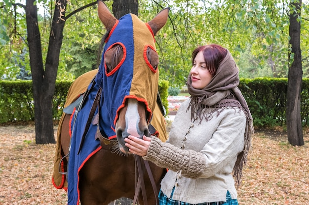 Piękna dziewczyna w starych rosyjskich ciuchach pieści swojego ulubionego konia