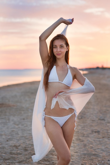 Piękna dziewczyna w stroju kąpielowym na plaży o zachodzie słońca