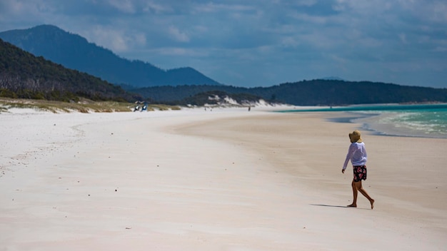 piękna dziewczyna w sukience i koszuli i kapeluszu spaceruje po plaży whitehaven, wyspa whitsunday, australia