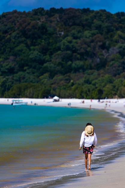 piękna dziewczyna w sukience i koszuli i kapeluszu spaceruje po plaży whitehaven, wyspa whitsunday, australia