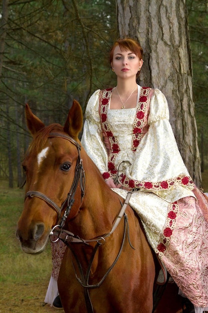 Zdjęcie piękna dziewczyna w zabytkowej sukience na koniu