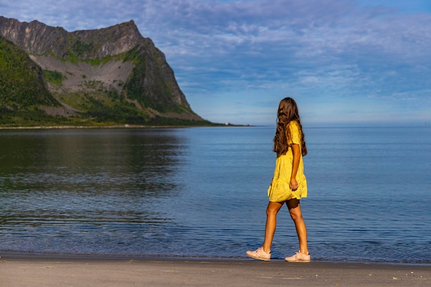 piękna dziewczyna w żółtej sukience spaceruje po plaży otoczonej potężnymi górami, senja, norwegia