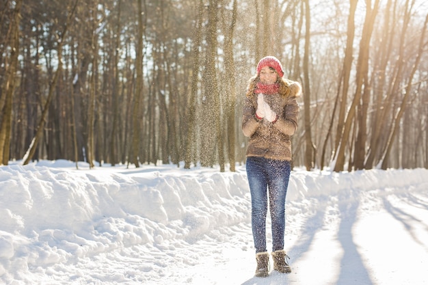 Piękna dziewczyna wiejący śnieg w mroźny winter Park. Na dworze. Latające płatki śniegu.