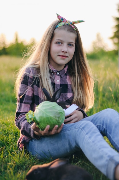 piękna dziewczyna z czarnym królikiem i kapustą w dłoniach.