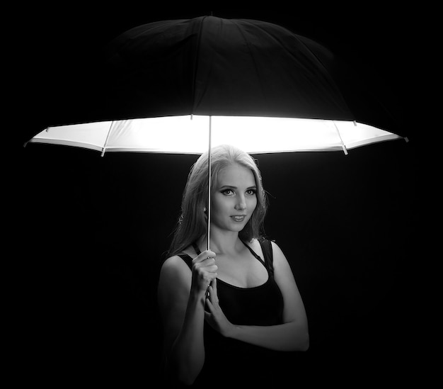 Piękna dziewczyna z czarnym parasolem na czarnym tle