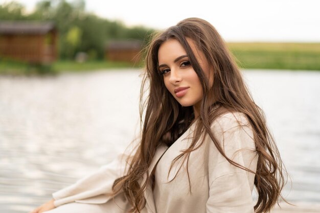 Piękna dziewczyna z długimi włosami pozująca na zewnątrz na brzegu jeziora