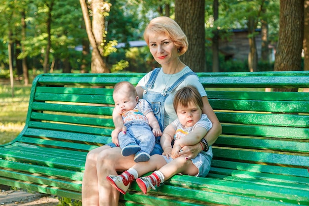 Piękna dziewczyna z dziećmi siedzi na ławce w parku