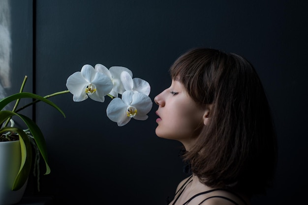 Piękna dziewczyna z tulipanem w orchidei piękna zmysłowa kobieta z kwiatem orchidei portret studyjny na czarnym