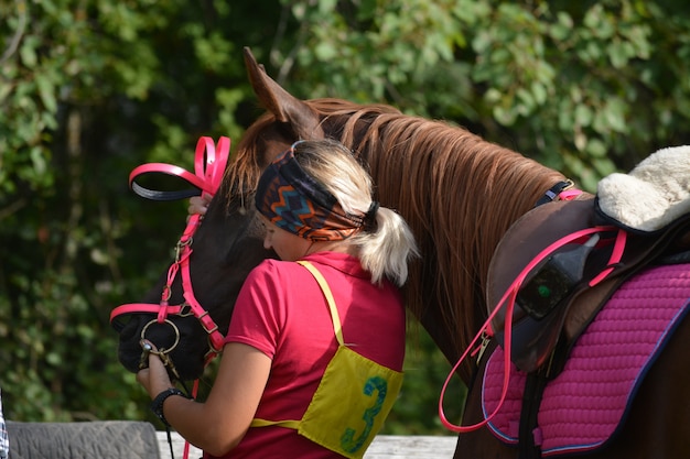 Zdjęcie piękna dziewczyna zakłada uzdę na konia.