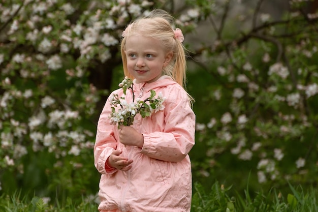 Piękna dziewczynka z dwoma ogonami cieszy się kwitnącymi jabłkami wiosennymi dziewczynkami przedszkolnymi w kwitnącym ogrodzie