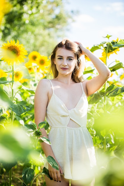Piękna europejska dziewczyna w białej sukni na charakter z słonecznikami