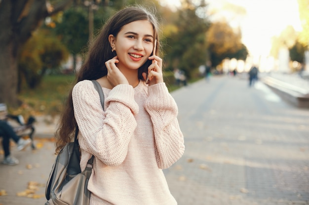 piękna i długowłosa dziewczyna spaceru po wiosnę słoneczne miasto i korzystania z telefonu