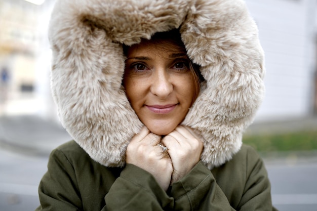 Zdjęcie piękna i ładna kobieta w średnim wieku, która chroni się przed zimnem w zimie płaszczem z futrem