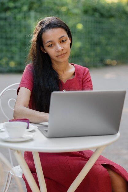 Piękna i młoda kobieta z Tysiąclecia w miejscu publicznym pracuje na laptopie afroamerykanin