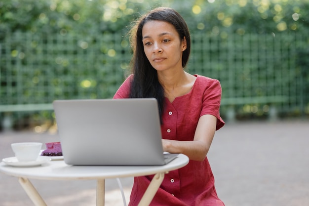 Piękna I Młoda Kobieta Z Tysiąclecia W Miejscu Publicznym Pracuje Na Laptopie Afroamerykanin