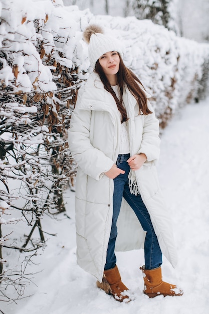Piękna i modna kobieta w białym ciepłym ubraniu chodzącym w śnieżnej pogodzie.