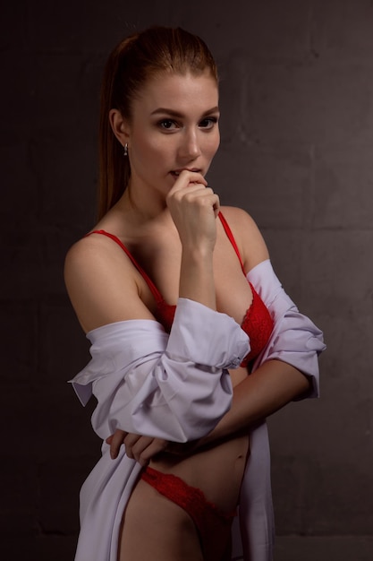 Piękna i seksowna dziewczyna w białej koszuli i czerwonej bieliźnie