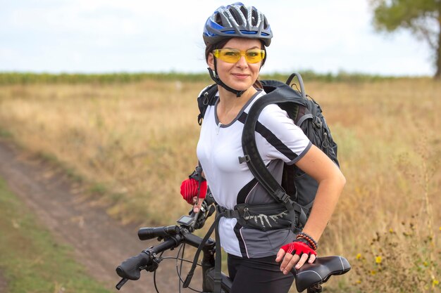 Piękna i szczęśliwa kobieta rowerzysta z rowerem na naturze. Zdrowy tryb życia i sport. Wypoczynek i hobby