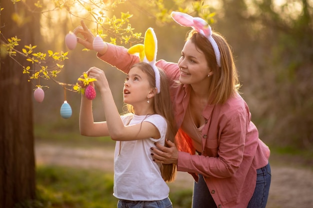 Piękna i szczęśliwa mama i córka w uszach królika dekorują choinkę pisanki szczęśliwa rodzina świętuje Wielkanoc