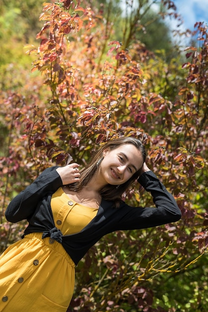 Piękna i urocza dziewczyna w pobliżu kolorowego krzewu liści w parku