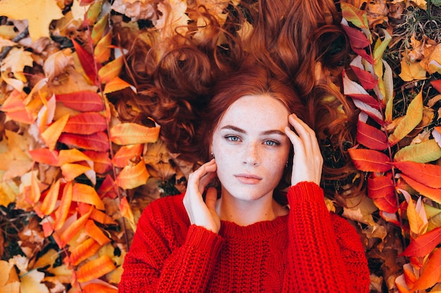 Piękna imbirowa kobieta z piegami na zewnątrz w parku jesień. Piękna twarz kobiety, koncepcja naturalnego piękna