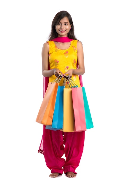 Piękna indyjska młoda dziewczyna trzyma i pozuje z torby na zakupy na białym
