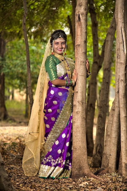 Piękna indyjska panna młoda w tradycyjnym saree pozująca na świeżym powietrzu w parku